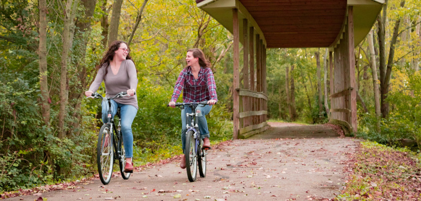 Two young women biking through a bridge