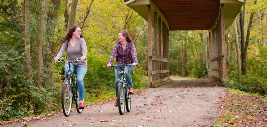 Two young women biking through a bridge